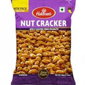 A 100g bag of Halkaram's Nut Cracker (spicy coated peanuts) on a plain white background. The packaging is primarily purple with a yellow 'NEW PACK' banner, a red Halkaram's logo, and a clear window displaying the golden-brown peanuts inside.