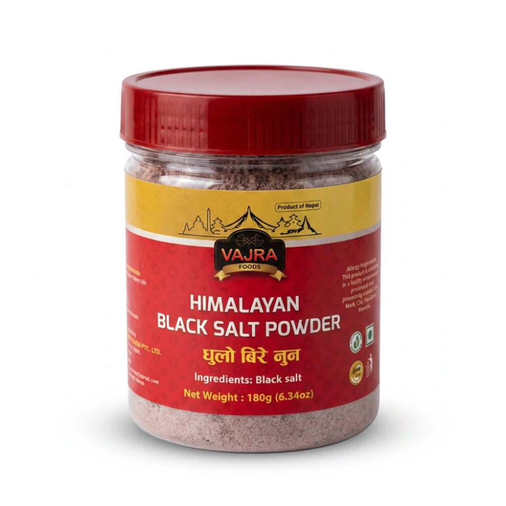 A jar of Vajra Foods Himalayan Black Salt Powder with a red lid and a red and yellow label, set against a plain white background.